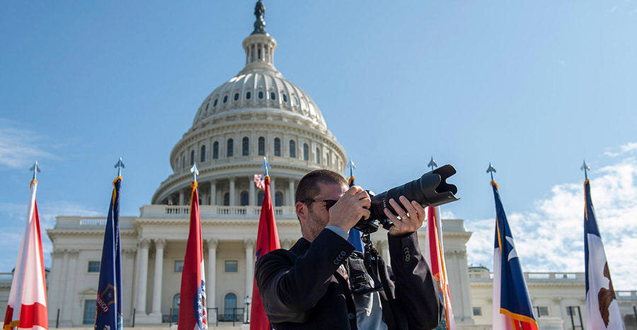 Secret Service photographer in front of the US Capitol and flags