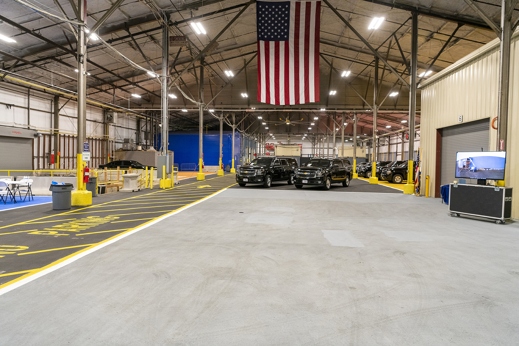 Two protective vehicles parked under an American flag in a commercial building.
